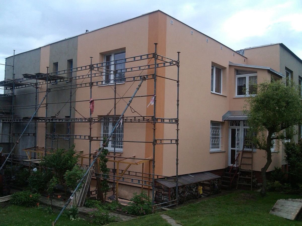Činžovní dům se zateplenou fasádou v meruňkové barvě, část pod lešením – realizace